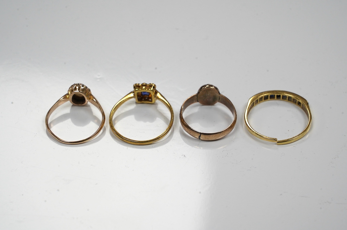 Four assorted gem set rings, including 18ct and plat, sapphire and diamond cluster, 14k, white opal and diamond cluster, an 18ct sapphire and diamond (cut) and an antique garnet set yellow metal ring. Condition - poor to